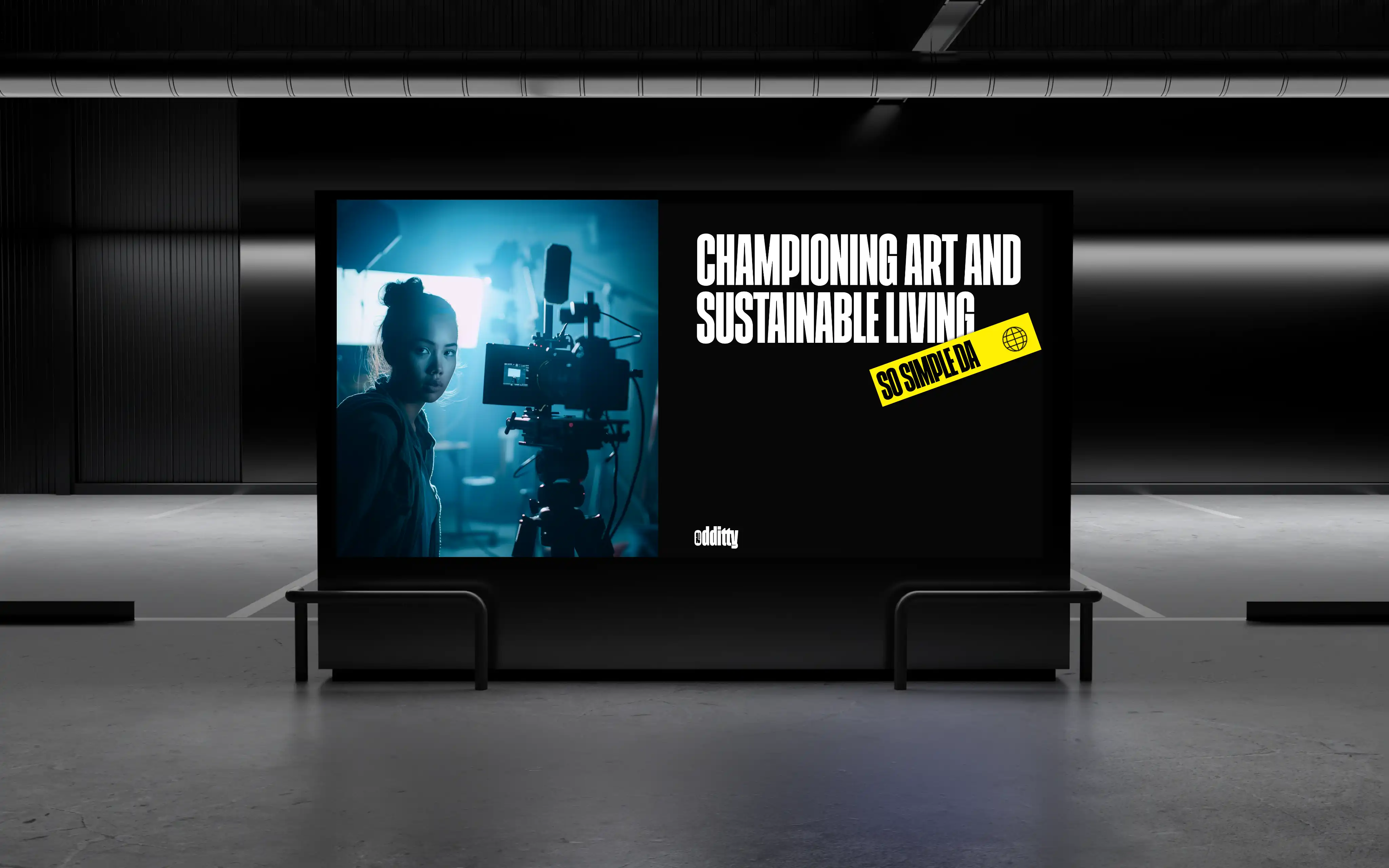 An Oddity billboard in an underground hall: a photograph of an artist with a camera beside the line Championing art and sustainable living.